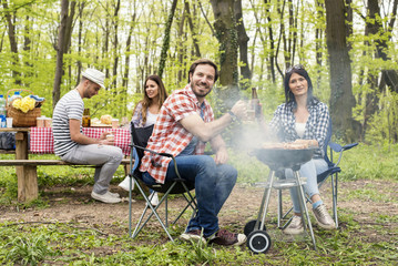 Two couples making barbecue and having fun outdoor