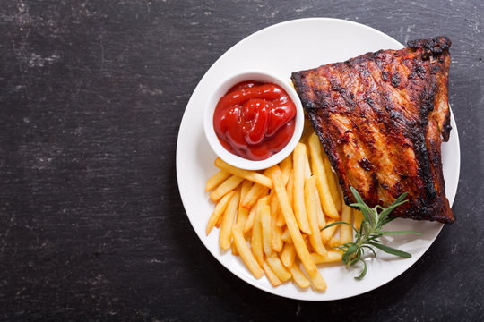 plate of grilled pork ribs with french fries, top view