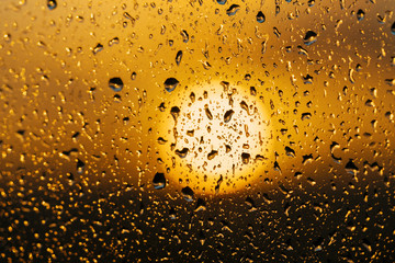 Abstract close up photo of water drops on window in front of a sunset.