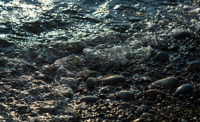 pebble stones on the sea beach, the rolling waves of the sea with foam