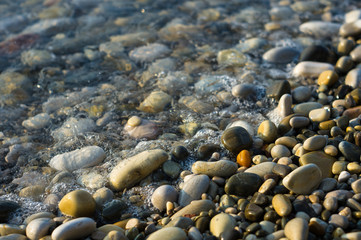 pebble stones on the sea beach, the rolling waves of the sea with foam