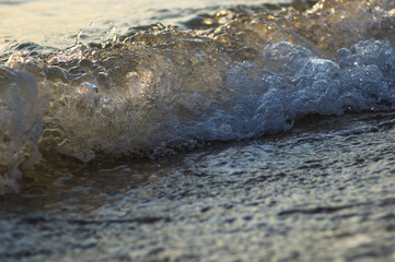 pebble stones on the sea beach, the rolling waves of the sea with foam