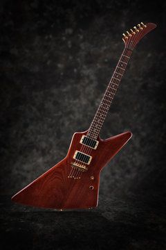 Electric guitar with natural finish isolated on dark grunge background, low key