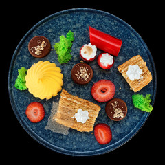 Set of various desserts in stone plate isolated on black