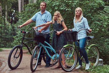 Obraz premium Attractive family dressed in casual clothes on a bicycle ride with their cute little spitz dog.