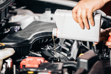 Pouring oil to car engine, close up