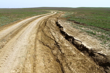 Unpaved broken dry dirt country road in steppe, offroad drive