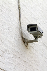 White video surveillance camera on the white dusty wall
