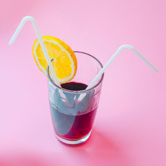 Fresh Juice glass with a two straw slice of yellow lemon on a pink background. Fashion pastel summer design style concept