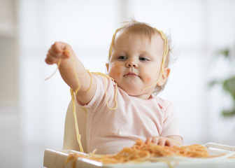 Little baby girl eating her lunch and making a mess