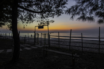 Naklejka na ściany i meble Exit door to the beach with fence and pine tree in the morning sky