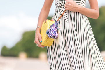 Woman with fashionable stylish yellow rattan bag and silk scarf outside. Tropical island of Bali, Indonesia. Rattan handbag and silk scarf.