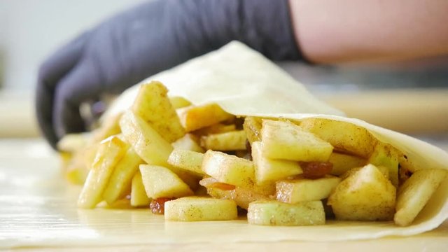 Cook prepares fresh apple in dough for pie strudel