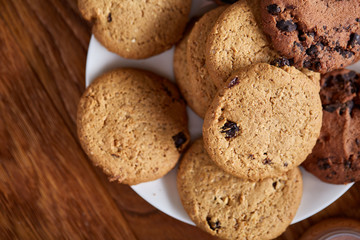 Side view of chocolate chip cookies on a wooden plate over rustic background, selective focus