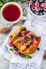 Healthy summer breakfast, baked french toasted bread sticks with fresh berry and honey, morning...