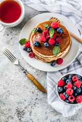 Healthy summer breakfast,homemade classic american pancakes with fresh berry and honey, morning light grey stone background copy space above