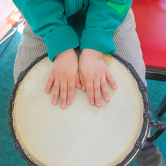 The boy plays percussion. Hands of a child and a drum.