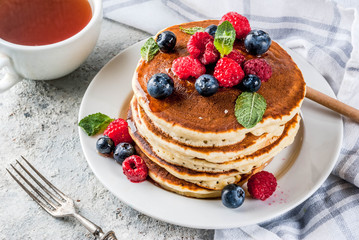 Healthy summer breakfast,homemade classic american pancakes with fresh berry and honey, morning light grey stone background copy space