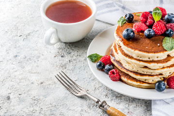 Healthy summer breakfast,homemade classic american pancakes with fresh berry and honey, morning light grey stone background copy space