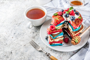 American Independence Day July 4th breakfast idea, homemade white blue red striped pancakes with fresh whipped cream, berry and honey, morning light grey stone background copy space