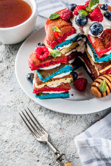 American Independence Day July 4th breakfast idea, homemade white blue red striped pancakes with fresh whipped cream, berry and honey, morning light grey stone background copy space