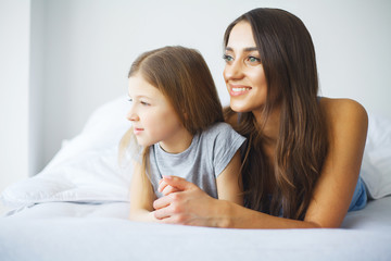 Young woman playing with little girl on bed