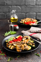 Grilled vegetable salad. Salad of barbecued zucchini, eggplant, sweet pepper, onion and mushrooms on black plate