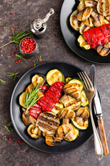 Grilled vegetable salad. Salad of barbecued zucchini, eggplant, sweet pepper, onion and mushrooms on black plate