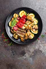 Grilled vegetable salad. Salad of barbecued zucchini, eggplant, sweet pepper, onion and mushrooms on black plate
