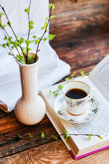 open book, coffee mug, branches with green leaves, the concept of love for reading, spring and freshness