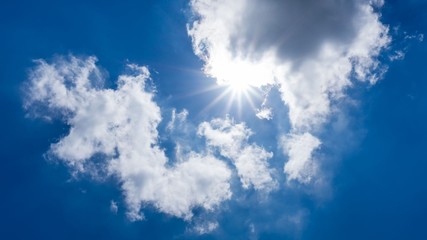 Naklejka na ściany i meble sun shining behind cloud on blue sky background