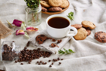 Morning coffee in white cup, chocolate chips cookies on cutting board close-up, selective focus