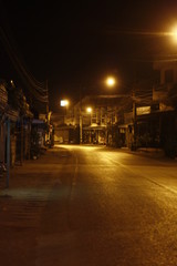 Fototapeta na wymiar remote thai town main street at night time with rows of yellow shining street lights, Northern Thailand, Southeast Asia