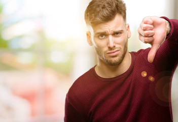 Handsome young man showing thumbs down unhappy sign of dislike, negative expression and disapproval