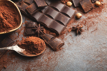 Crushed chocolate bar pieces and cocoa on gray background