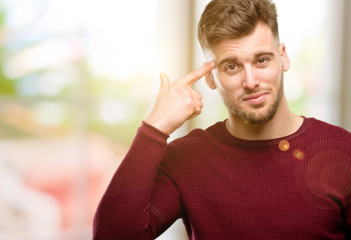 Handsome young man unhappy making suicide gesture, tired of everything. Shoots with his hand...