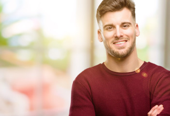 Handsome young man with crossed arms confident and happy with a big natural smile laughing