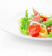 Fresh salad with tomatoes, arugula, cheese and ham on the white plate and white background