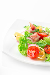 Fresh salad with tomatoes, arugula, cheese and ham on the white plate and white background
