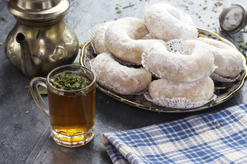 Oriental Algerian sweet cookies( gazelle horns cookies ), tea cup and pot  and mint leaves - obrazy, fototapety, plakaty