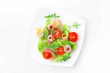Fresh salad with tomatoes, arugula, cheese and ham on the white plate and white background