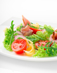 Fresh salad with tomatoes, arugula, cheese and ham on the white plate and white background