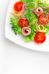 Fresh salad with tomatoes, arugula, cheese and ham on the white plate and white background