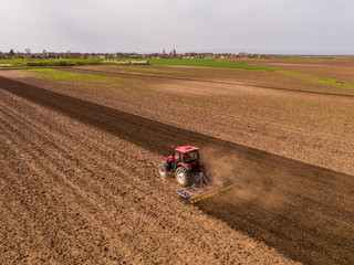 Aerial shot of a tractor cultivating field at spring