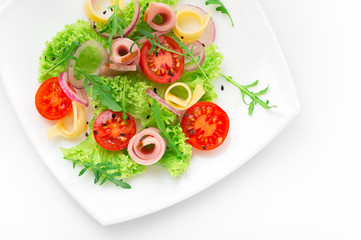 Fresh salad with tomatoes, arugula, cheese and ham on the white plate and white background