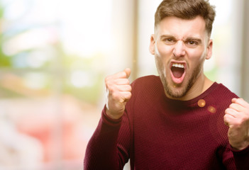 Handsome young man happy and excited celebrating victory expressing big success, power, energy and positive emotions. Celebrates new job joyful