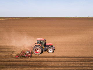 Obraz premium Aerial shot of a tractor cultivating field at spring