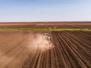 Aerial shot of a tractor cultivating field at spring