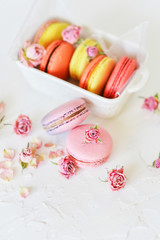 Dessert: A Delicate Fresh French Macaroons In Pastel Colors Gift Box With Flowers Roses On A Light Textile Background