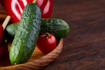Wooden plate with vegetables for a vegetarian salad on rustic wooden background, close-up, selective focus